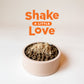 Beige pet bowl filled with dark brown kibble and a pile of light brown freeze-dried raw cat food topper.