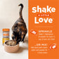 Calico cat eating Instinct Raw Boost Shakers chicken cat food topper from a beige bowl, next to the product jar.