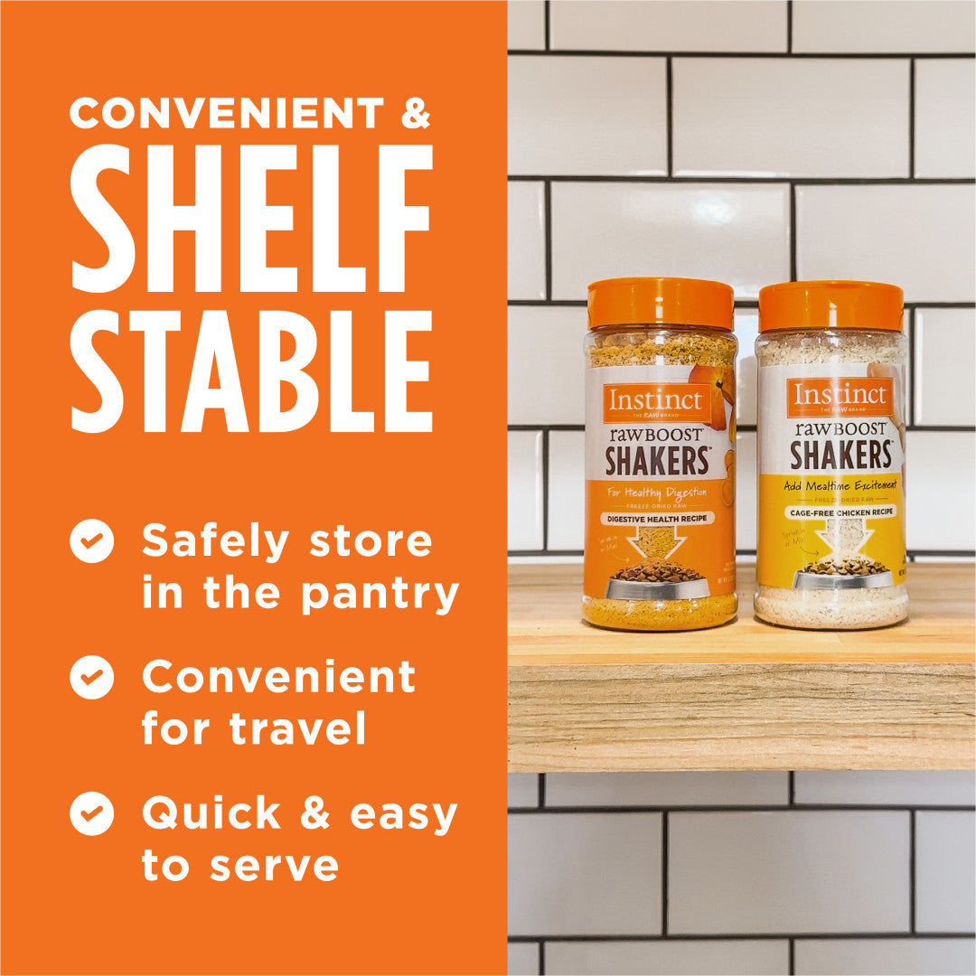Two clear Instinct Raw Boost Shakers cat food toppers with orange lids on a wooden shelf against white tiles.