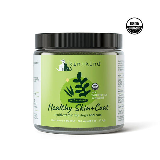 Kin+Kind Healthy Skin+Coat multivitamin for dogs and cats in a clear jar with a black lid, featuring green label with wheatgrass and seaweed.