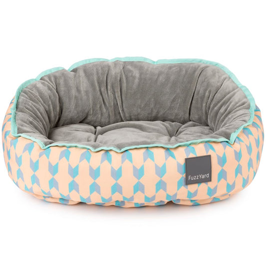 Reversible FuzzYard Chelsea dog bed with pastel peach and blue geometric patterns, soft grey plush interior.